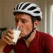 Leeggereden wielrenner in rood shirt drinkt thuis een glas magere melk na een trainingsrit.