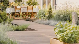 Plants and wooden chairs at table with food on terrace of house in the summer