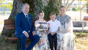 Foto van prins Albert, prinses Gabriella, prins Jacques en prinses Charlene op een bankje onder een boom, juli 2025.