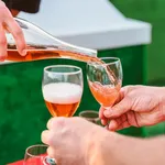 the pouring of fruit cider into two glasses in the hands