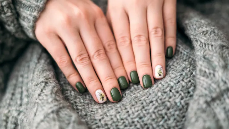 Women's hands with stylish green autumn manicure, against the background of a warm knitted plaid. autumn season. Close-up. nail art