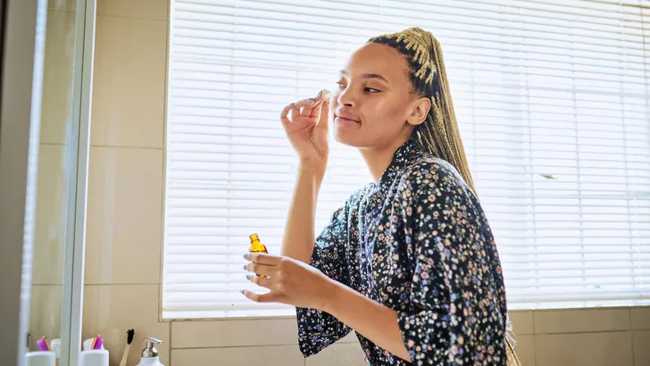 Shot of a beautiful young woman using a face serum as part of her beauty regime