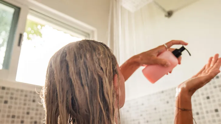 Woman takes shower and uses pink conditioner