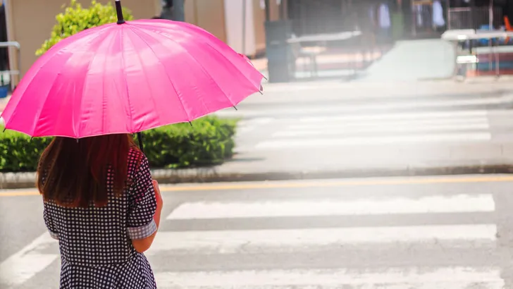 Woman with pink umbrella Going across the crosswalk