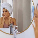 Shot of an attractive young woman inspecting her face in the bathroom mirror