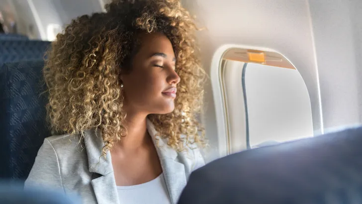 Commercial airline passenger sleeps in window seat