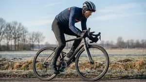 Mannelijke wielrenner zet kracht op de pedalen met een zwaar verzet tijdens een training op een heuvelachtige weg.