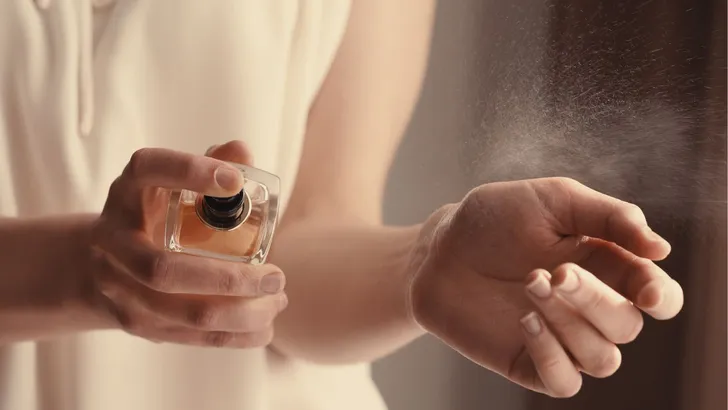 Een vrouw die parfum op haar pols spuit