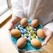 Top-down foto van vrouw met bord paaseitjes in haar handen. – Zoveel paaseitjes moet je eten om een kilo aan te komen