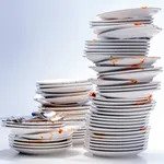 Dirty plates, glasses, cutlery on white background.