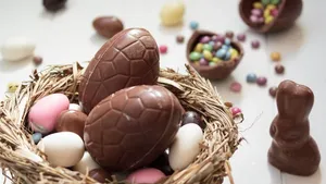 Delicious Chocolate eggs and easter almonds on nest, chocolate bunny and sweets on white wooden table