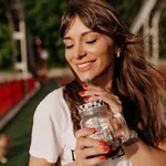 Close up outdoor portrait of beautiful lovely charming girl with long hair closed eyes and smiling while drinking morning coffee