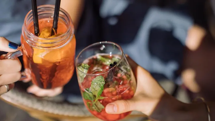 Women holding glasses of summer cocktails and toasting. Healthy lifestyle concept. Outdoors.