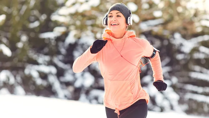 Woman jogging in the snow on the nature in winter