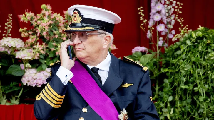 Foto van prins Laurent van België, telefonerend op het podium tijdens de viering van de Nationale Dag in 2022.
