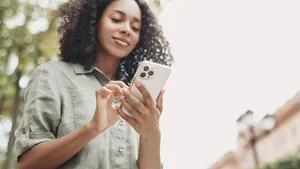 Young beautiful woman using smartphone in a city. Smiling student girl texting on mobile phone outdoor. Modern lifestyle, connection, casual business concept