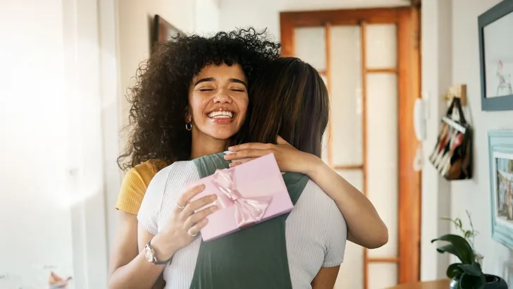 Iemand geeft een cadeau aan vriendin.