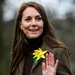 Kate buiten zwaait in groene jas met bloem op kraag