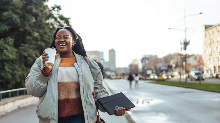 Beautiful young african american woman holding a coffee to go