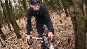 Oud-profwielrenner Ide Schelling in volle actie tijdens een tracklocross-race, terwijl hij geconcentreerd door een modderige bocht glijdt op zijn fixed-gear fiets.