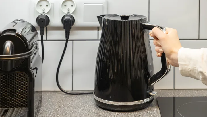 Zwarte waterkoker op aanrecht in keuken.