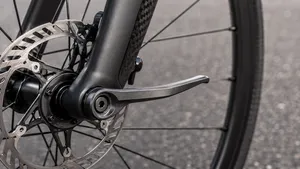 Close-up van het voorwiel van een racefiets, waarbij de hendel van de steekas gevaarlijk naar voren (in de rijrichting) wijst.
