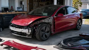 Zwaar beschadigde rode Tesla Model 3 staat in een particuliere garage