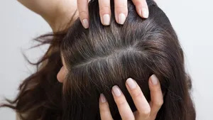 The woman shows gray hair on her head. Hair with fragments of gray hair, hair roots requiring dyeing