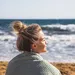 Een vrouw bij de zee met een messy bun.