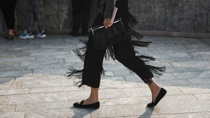 Foto van vrouw met ballerina schoenen en stijlvolle pantalon tijdens Fashion Week.