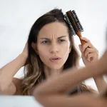 Woman looks in mirror combing hair feels dissatisfied hair condition