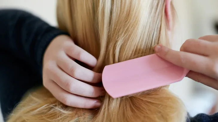 Rearview of young blonde woman brushing hair