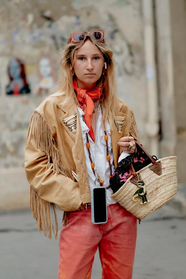 Blonde vrouw met oranje sjaaltje om haar nek, zonnebril en earpods