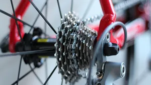 Close-up van de aandrijflijn van een racefiets in de schuur, waarbij de ketting op het grote buitenblad en een medium achtertandwiel ligt, wat onnodige spanning op de derailleurs veroorzaakt.