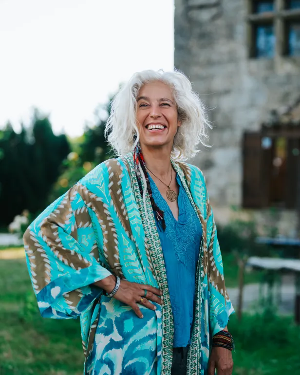 Nisha Tara van B&B Vol Liefde 2026 kijkt lachend in de camera en poseert voor haar gastenverblijf in Lot-et-Garonne, Frankrijk.
