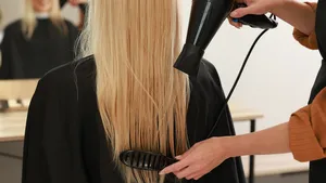 Foto van vrouw met lang blond kapsel in kappersstoel.