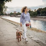 Beautiful woman walking her dog by the river