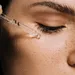 Vrouw die serum aanbrengt met pipet op gezicht - vitamine c