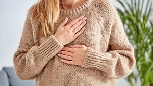 Young woman with heart problem holding chest.