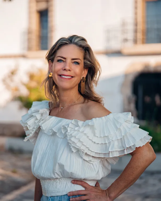 Iris poseert in een witte top met ruffles voor haar Soulfarm in Catalonië, Spanje voor B&B Vol Liefde 2026.