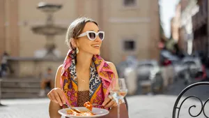 Woman eating italian pasta at restaurant on the street in Rome