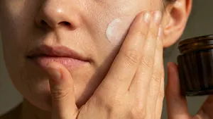 Vrouw smeert rijke gezichtscrème met ceramiden op voor een gehydrateerde huid.