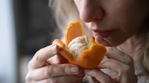Vrouw in de overgang probeert de geur van verse mandarijn te herkennen.
