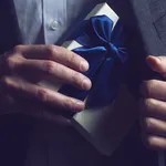 Man in suit opening a gift with blue ribbon