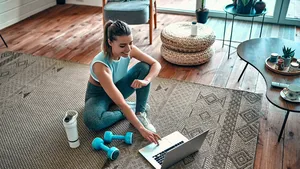 Vrouw in sportkleding thuis met gewichtjes op de grond