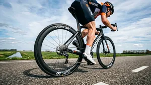 Mannelijke wielrenner met helm accelereert uit het zadel op zijn racefiets met focus op het achterwiel en de fietsband