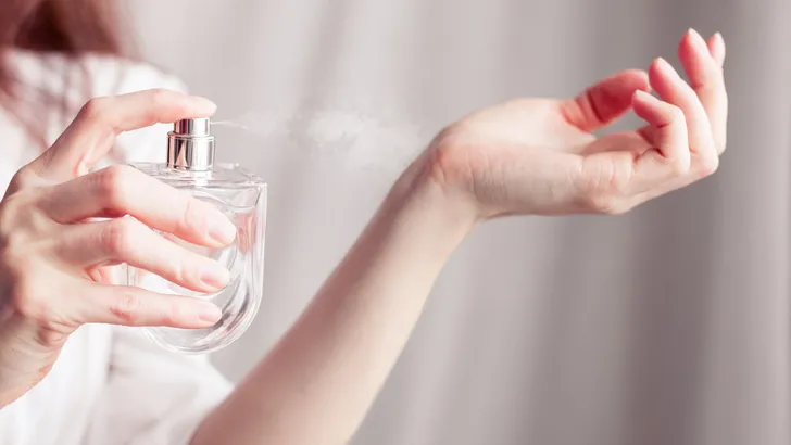 girl sprays herself perfume on her wrist
