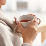 Beautiful young woman drinking tea at home, closeup