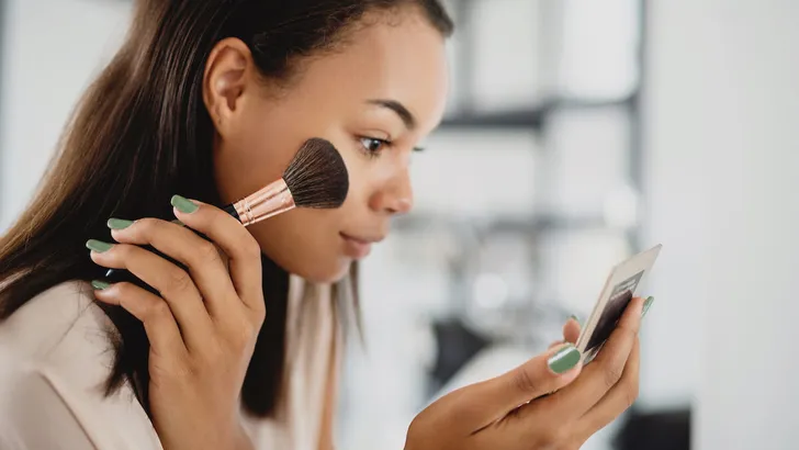 Portrait of young African woman doing applying makeup at home.