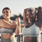 Shot of two young women stretching while outside for a workout